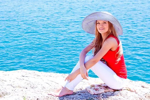 Young and beautiful girl resting on rocks against the sea