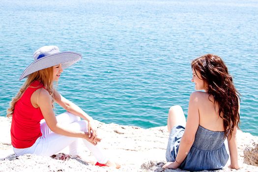 Two beautiful and young girl resting on a rocky coast