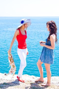 Two beautiful and young girl resting on a rocky coast