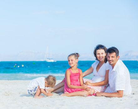 Family of four having fun on tropical beach