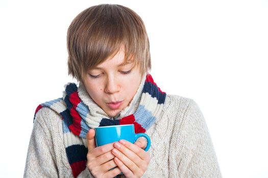 Portrait of young smiling cute frozen teenager in a scarf and with blue cup, isolated on white