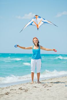 Young cute woman playing with a colorful kite on the tropical beach. Vertikal veiw