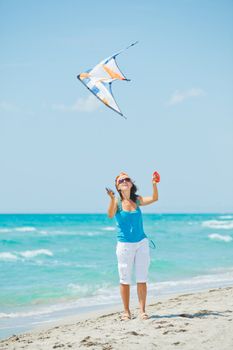 Young cute woman playing with a colorful kite on the tropical beach. Vertikal veiw