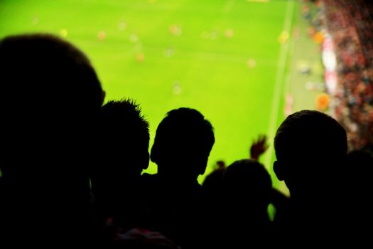 Silhouettes of fans celebrating a goal on football match