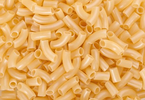 Fresh yellow pasta tubes on table