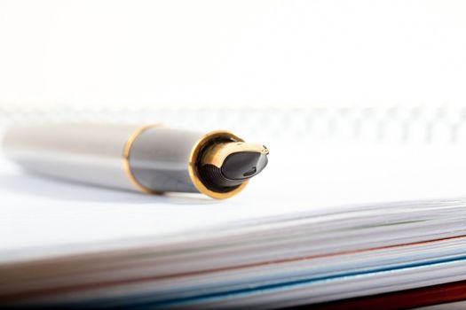 pen with feather lays on a writing-book with spiral