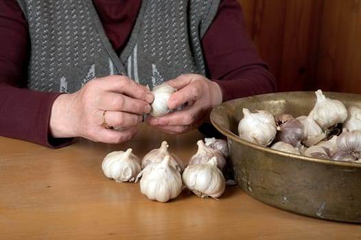 The old woman touches garlic sitting for a table