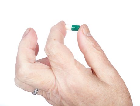 hand of the old woman holds capsule with medicines on a white background