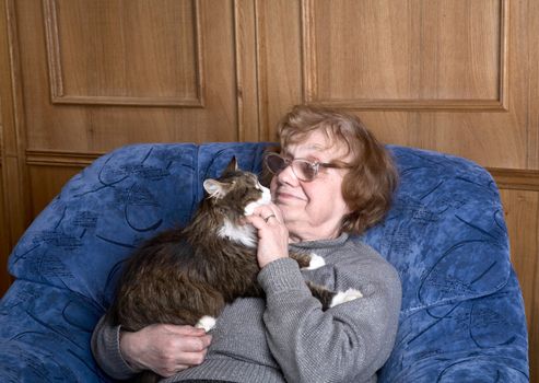 old woman in an armchair with a cat on hands