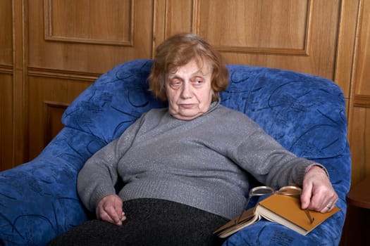 old woman in an armchair  glasses and with the book