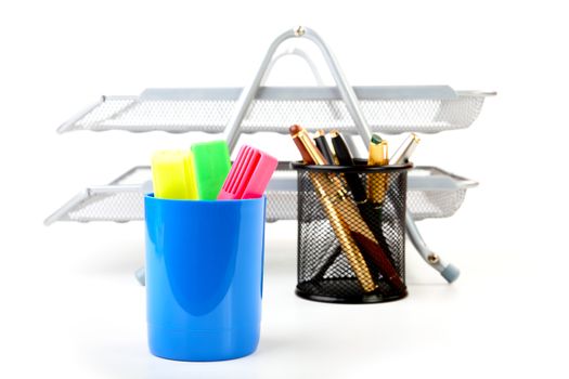 Markers and pens in a support against shelves for papers
