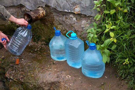 The female hand holds plastic bottle with water at a spring