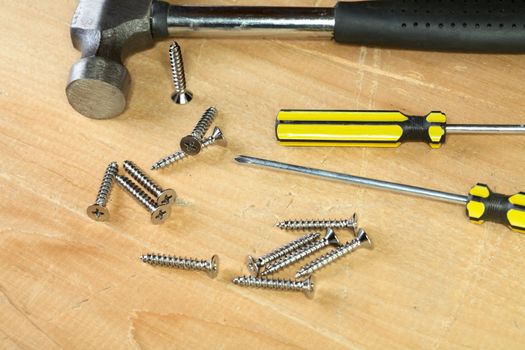 Hammer screw-driver screws on a wooden board