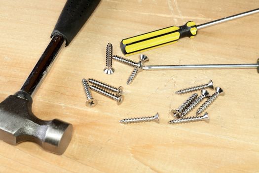 Hammer screw-driver screws on a wooden board