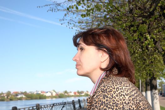 woman of average years looks at the river in  spring afternoon