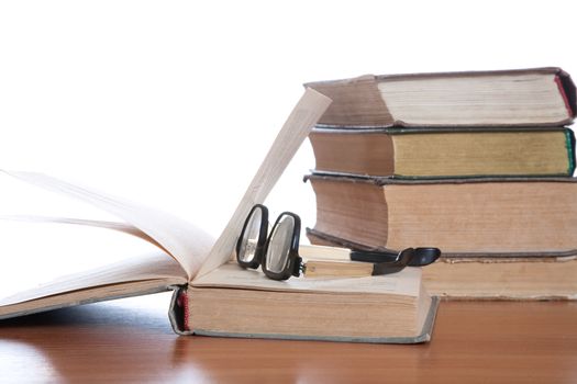 Old glasses and the old book on a white background
