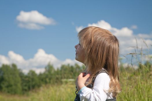 little girl looks at the sky with clouds
