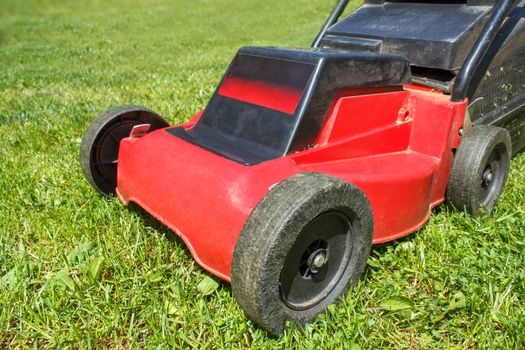 Detail of lawnmower on green grass in sunny day