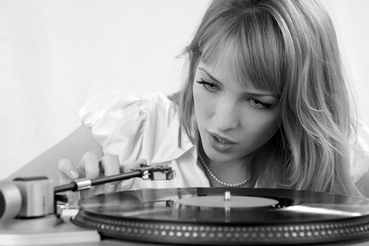 The girl listens to a vinylic disk black-and-white