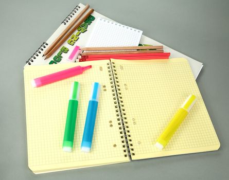 Markers pencils a writing-book on  grey background