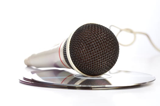 The microphone lays on  compact discs on  white background