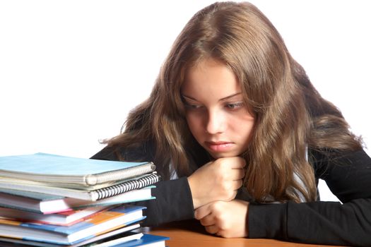 The girl-teenager looks at  pile of books on a white background