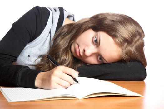 The girl-teenager looks in  writing-book on a white background