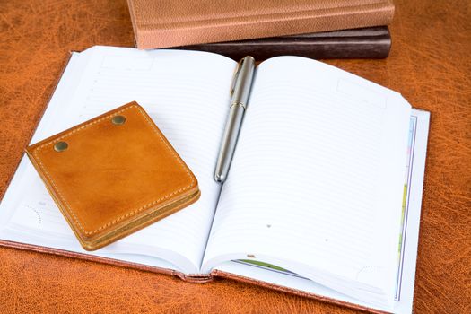 Leather organizers and fountain pen on a textural background