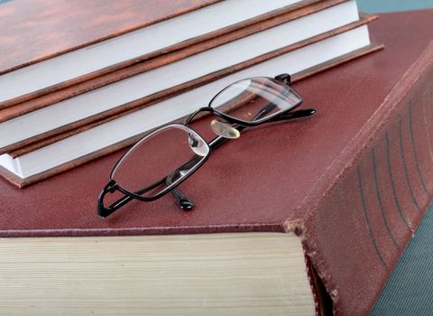 Pile of books and glasses on old thick volume