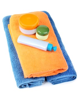 Terry towels and tubes with cosmetics isolated on a white background
