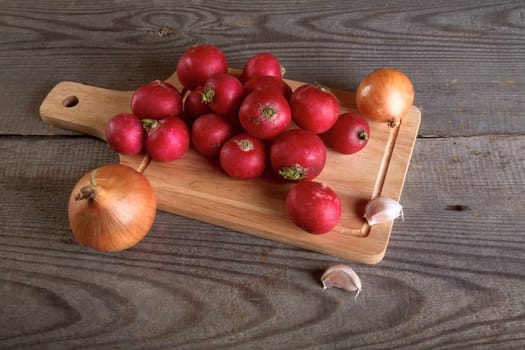 Onions garlic  garden radish on a table from unplaned boards