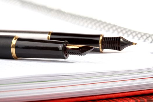 fountain pens lays on a writing-book with spiral