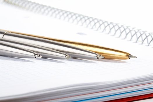 line of ball-point pens lays on a writing-book