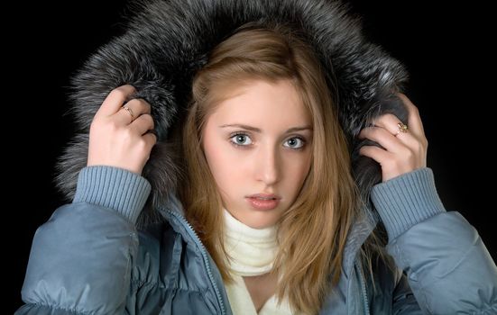 The girl in  warm jacket with a hood on  black background