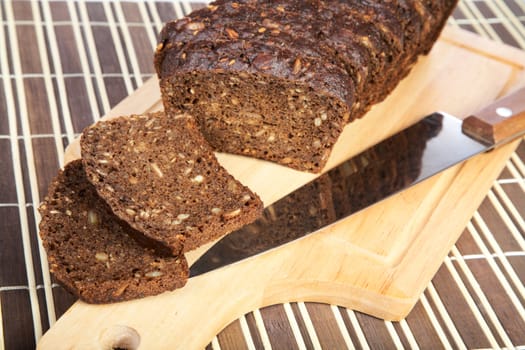 Slices cut black bread with  knife on a chopping board