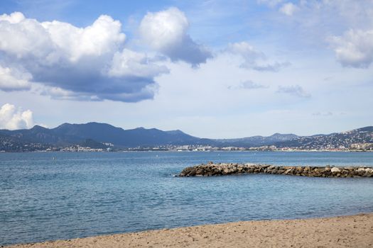 Beach with the mountains in the background on a partly cloudy day in the French Riviera near Cannes France