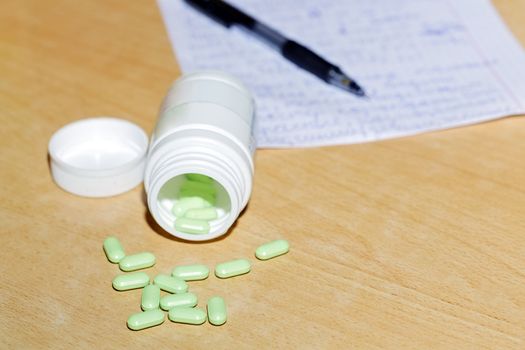 Medicine bottle and pills and note with a pen