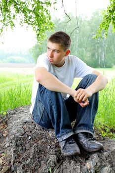 sad teenager sitting in the forest alone