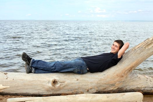 happy young man resting against seaside background