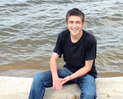 happy young man sitting near the water