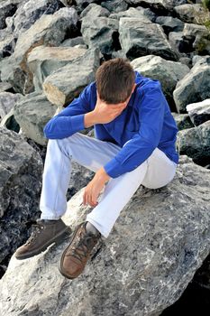 sad teenager sitting on the rocks