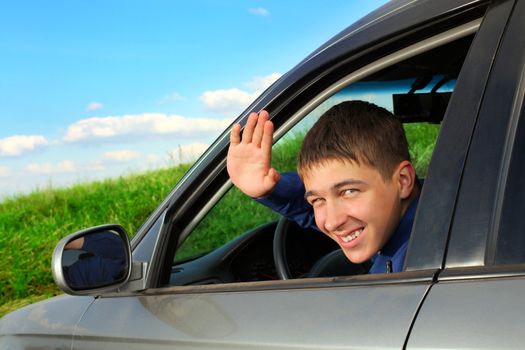 happy young man sitting in the car and wave goodbye