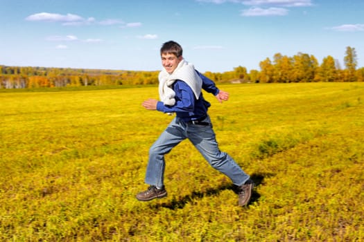 happy teenager running on the autumn field in motion blur