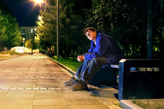 lonely teenager sitting in the night park alone