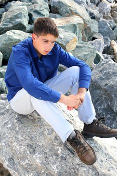 sad teenager sitting on the rocks