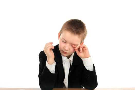 very sad schoolboy crying on the table isolated on the white background