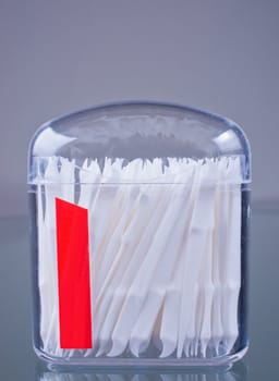 Plastic toothpicks in clear plastic container on grey background