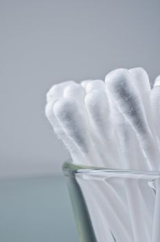 Cotton buds in a glass close up grey background