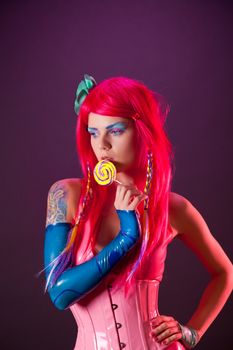 Bright girl with pink hair holding lollipop, studio shot 
