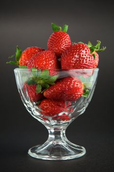 Strawberry in glass container on black background